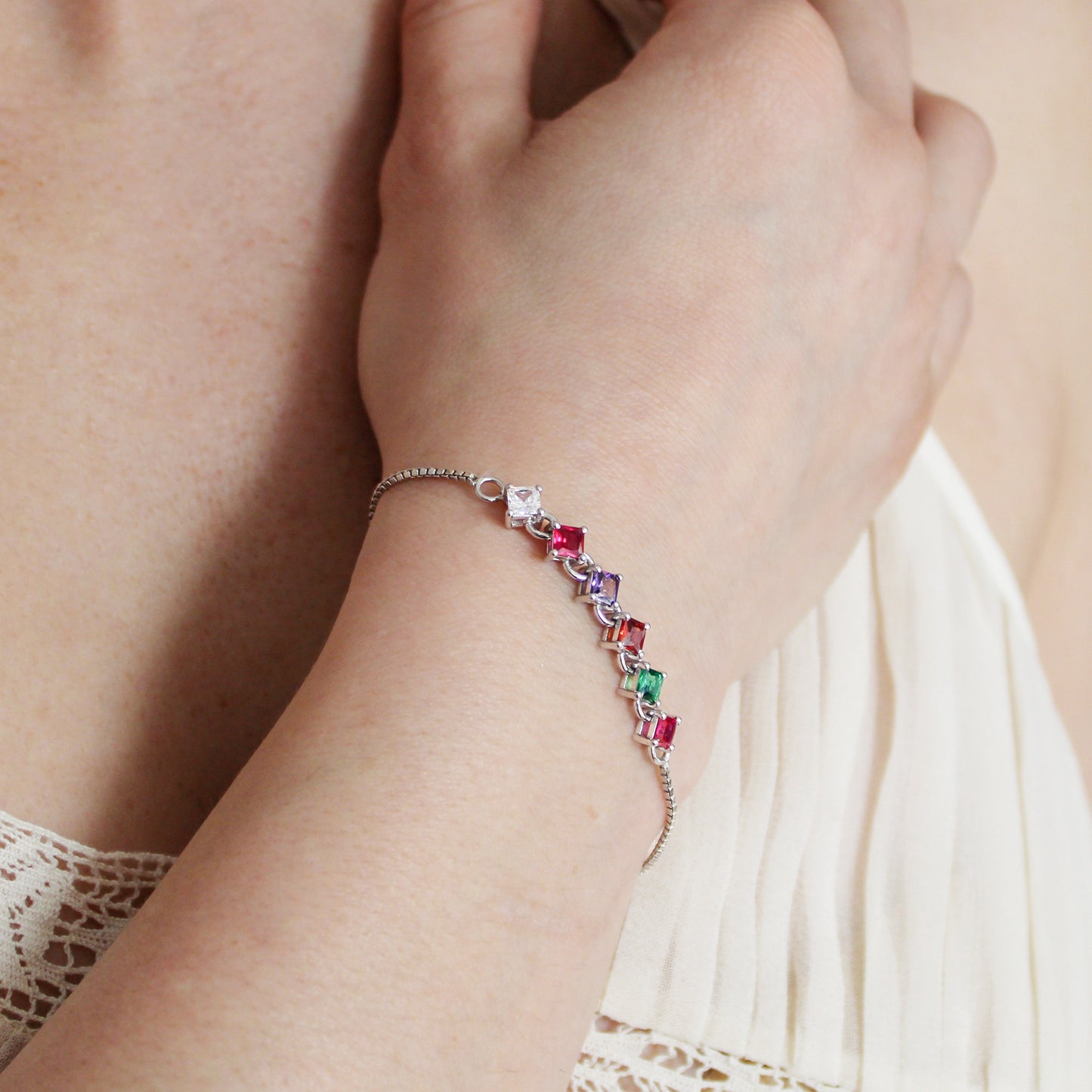 Sterling silver Linked Love Bracelet on model wrist against chest, square-cut REGARD acrostic CZ bracelet, Ether Jewelry