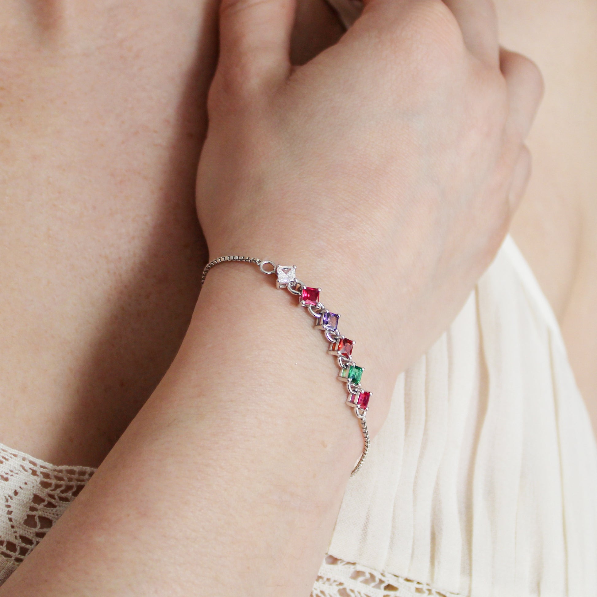 Sterling silver Linked Love Bracelet on model wrist against chest, square-cut REGARD acrostic CZ bracelet, Ether Jewelry