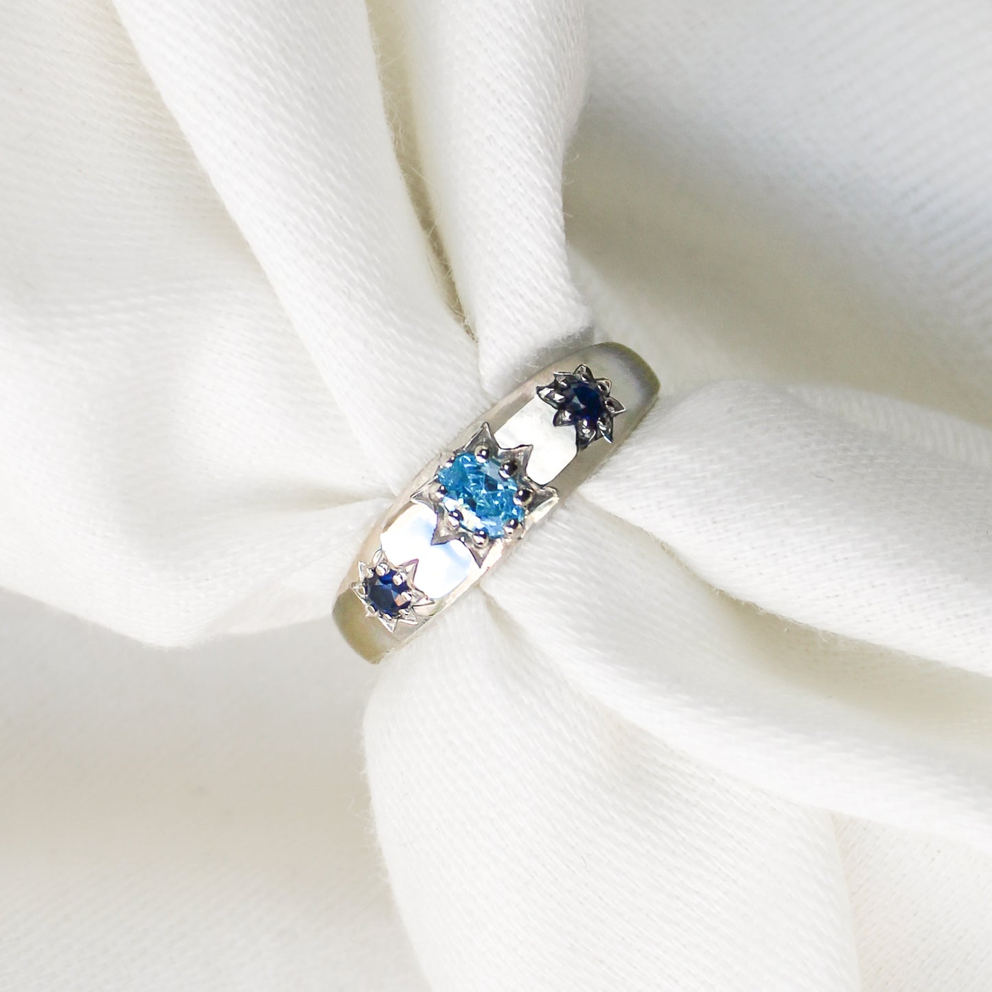 Letters from Roma Ring in sterling silver over white fabric, domed light blue and blue CZ gypsy band, Ether Jewelry