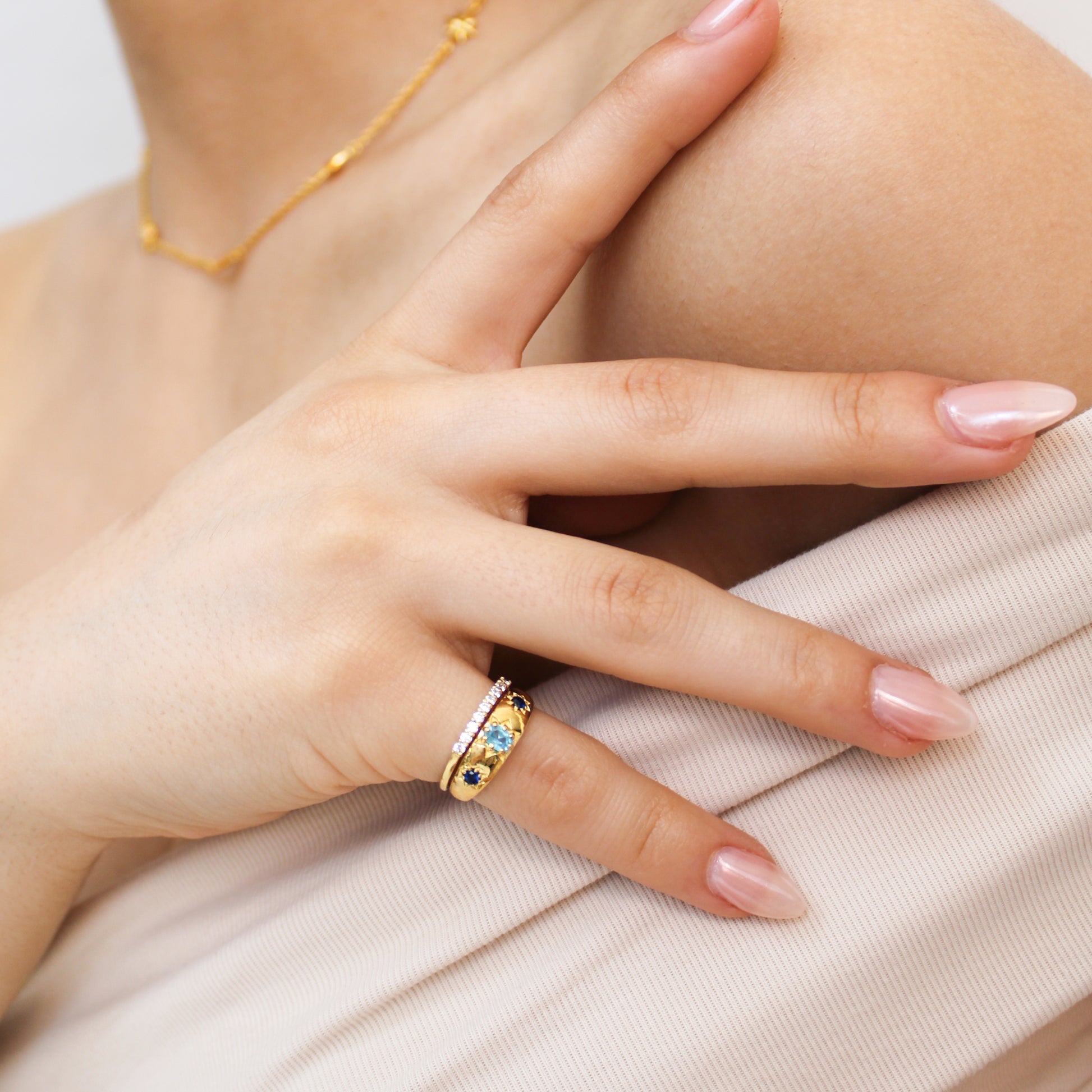 Letters from Roma Ring 18k gold vermeil close-up on model hand, domed light blue CZ center with star-set blue CZ stones, Ether Jewelry