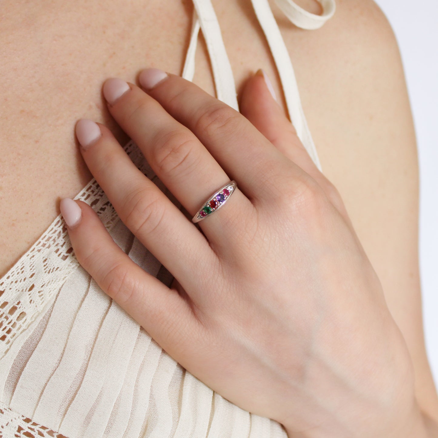 Love Letter Ring in sterling silver worn on model hand on chest in beige dress, acrostic REGARD ring, Ether Jewelry