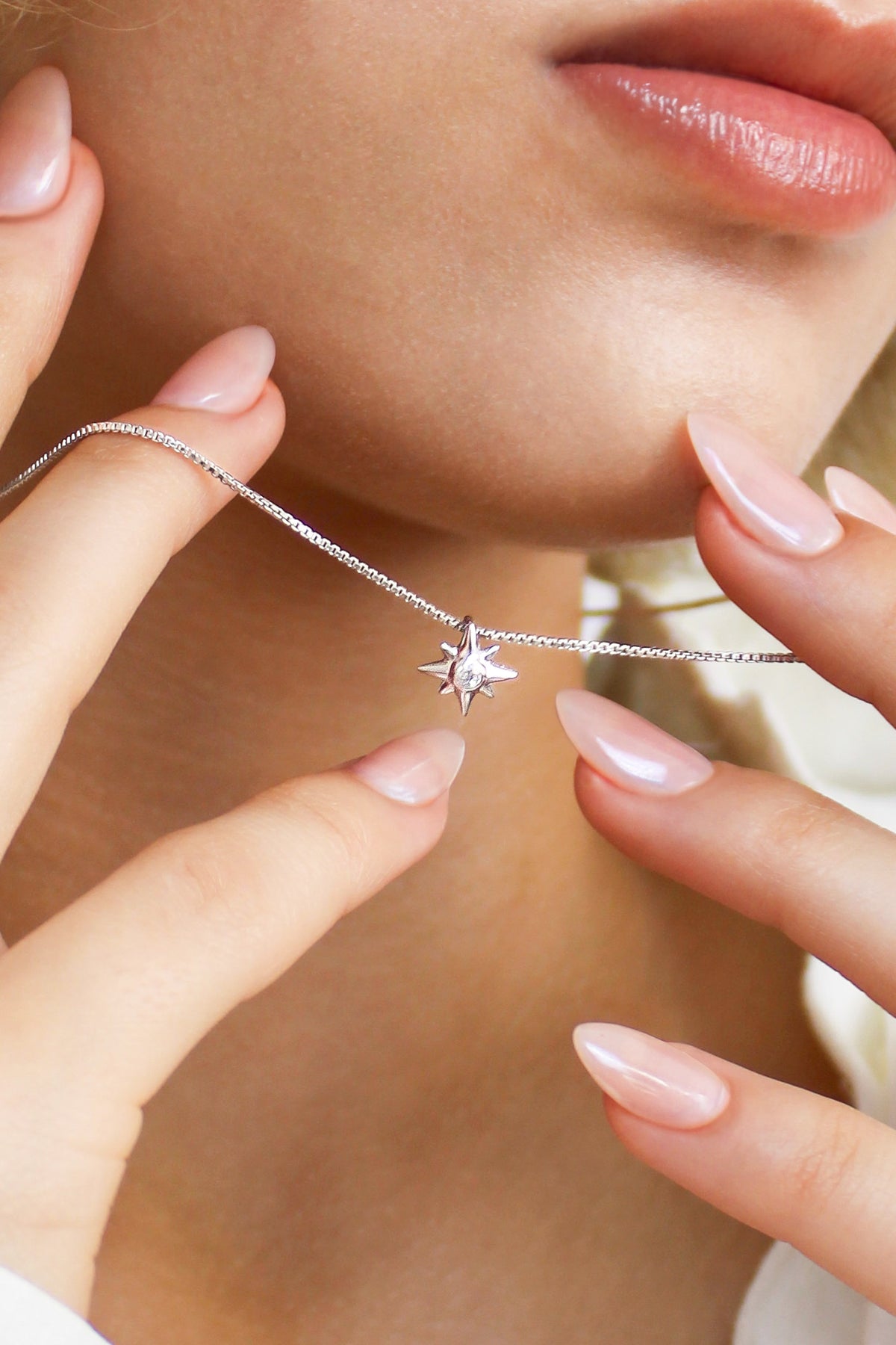 Lucida Necklace in sterling silver held up in front of model face, dainty north star CZ pendant on box chain, Ether Jewelry