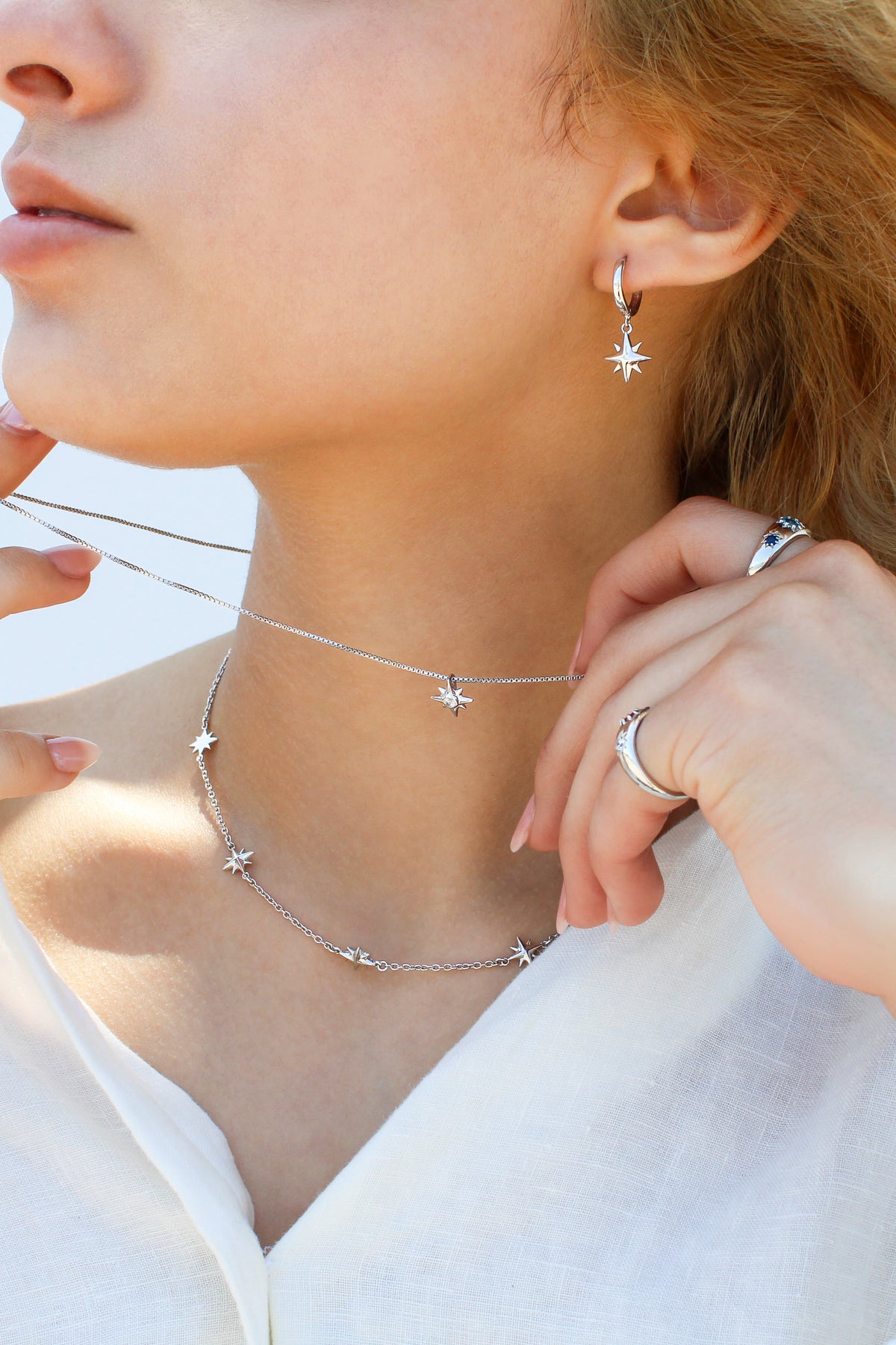 Lucida Necklace in sterling silver held up in front of model face, dainty north star CZ pendant on box chain, Ether Jewelry