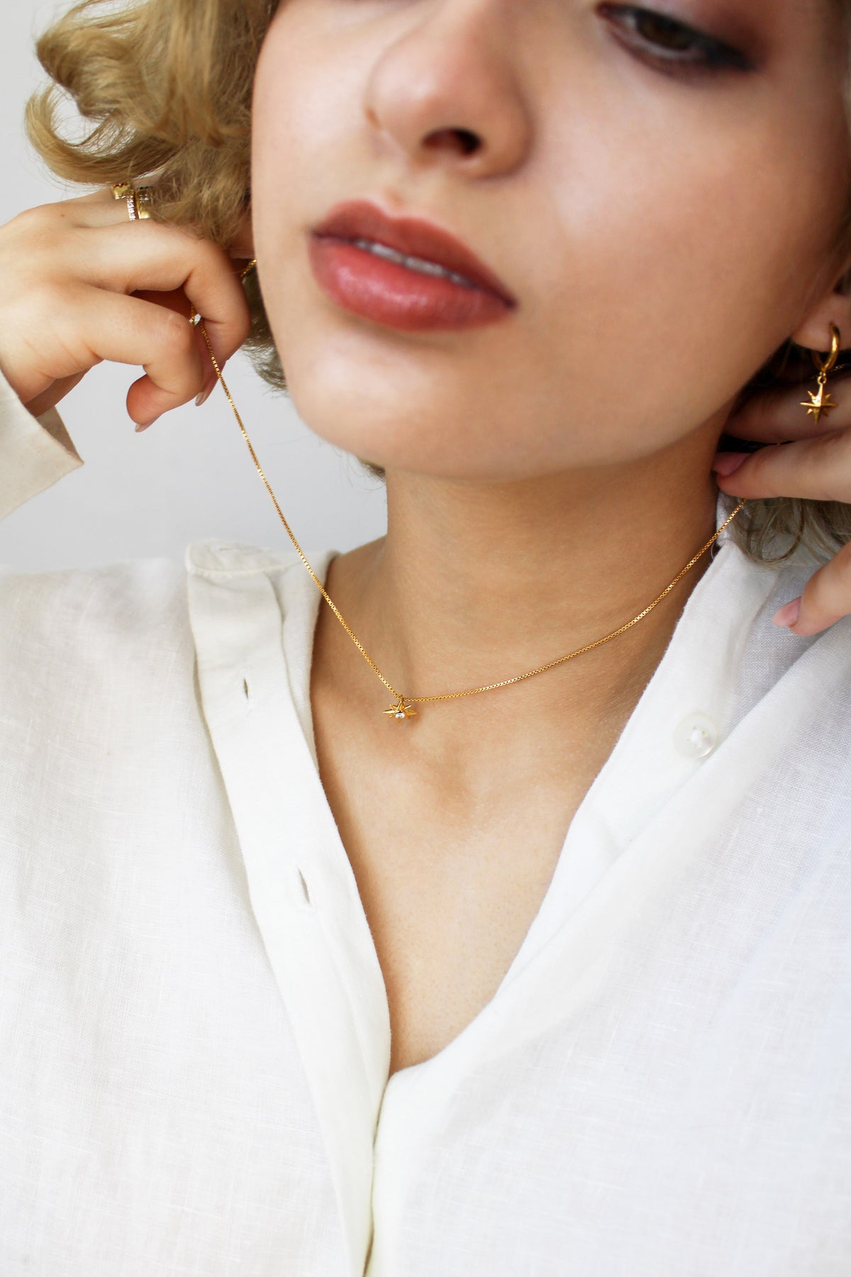 Lucida Necklace gold vermeil eight point star necklace, model putting on necklace, ether jewelry