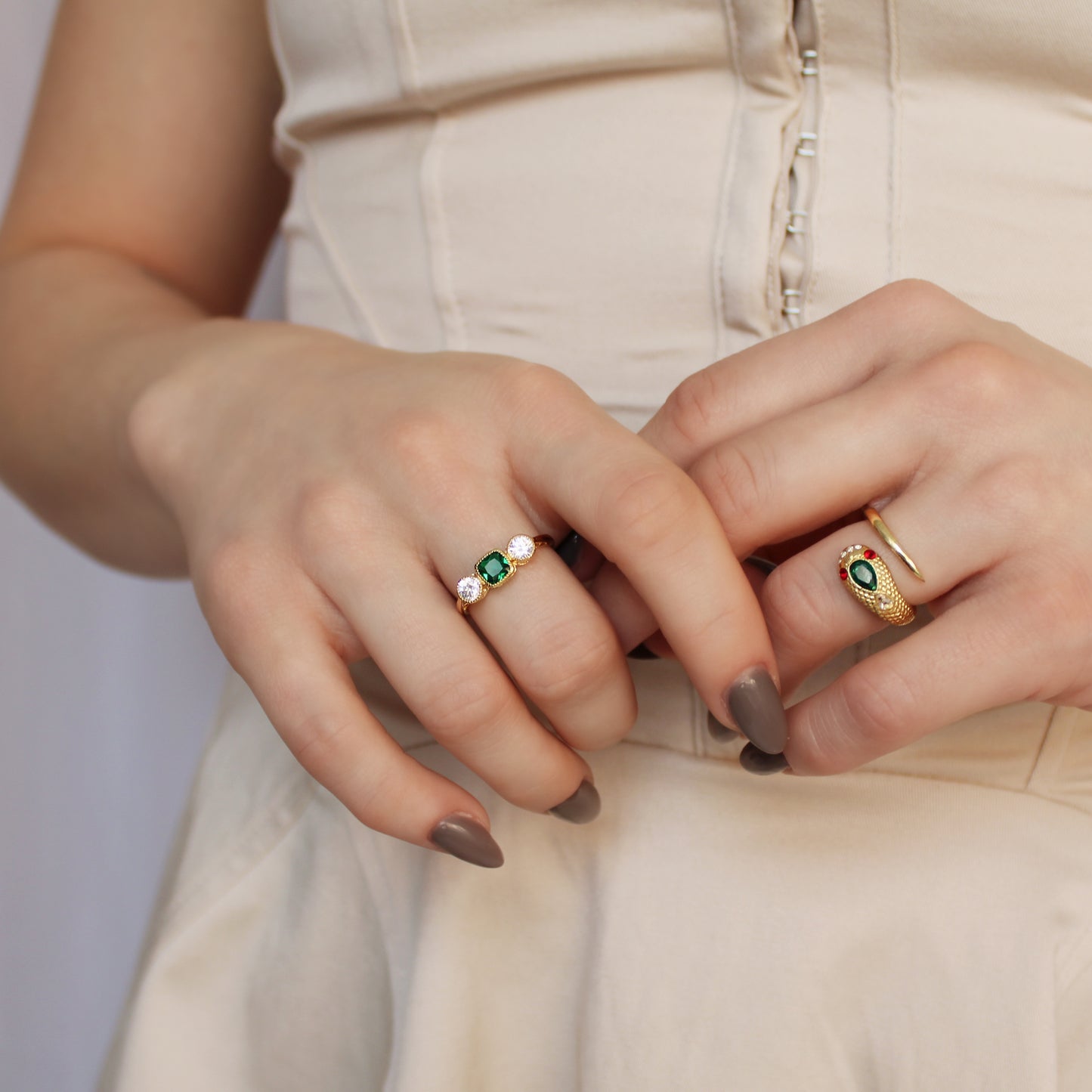 18k gold vermeil Edwardian Three Stone ring paired with another ring on model hands at stomach in beige dress, Ether Jewelry