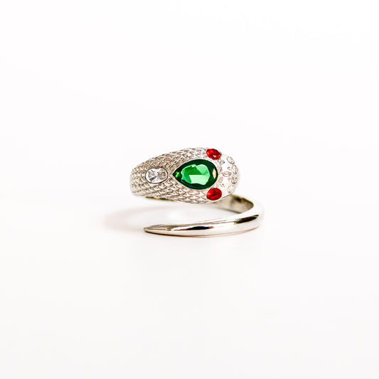 Queen Victoria Ring in sterling silver featuring a prominent green pear gemstone in the center, accented by two small red round gemstones and a clear round stone on the textured scales, set against a plain white background, ether jewelry
