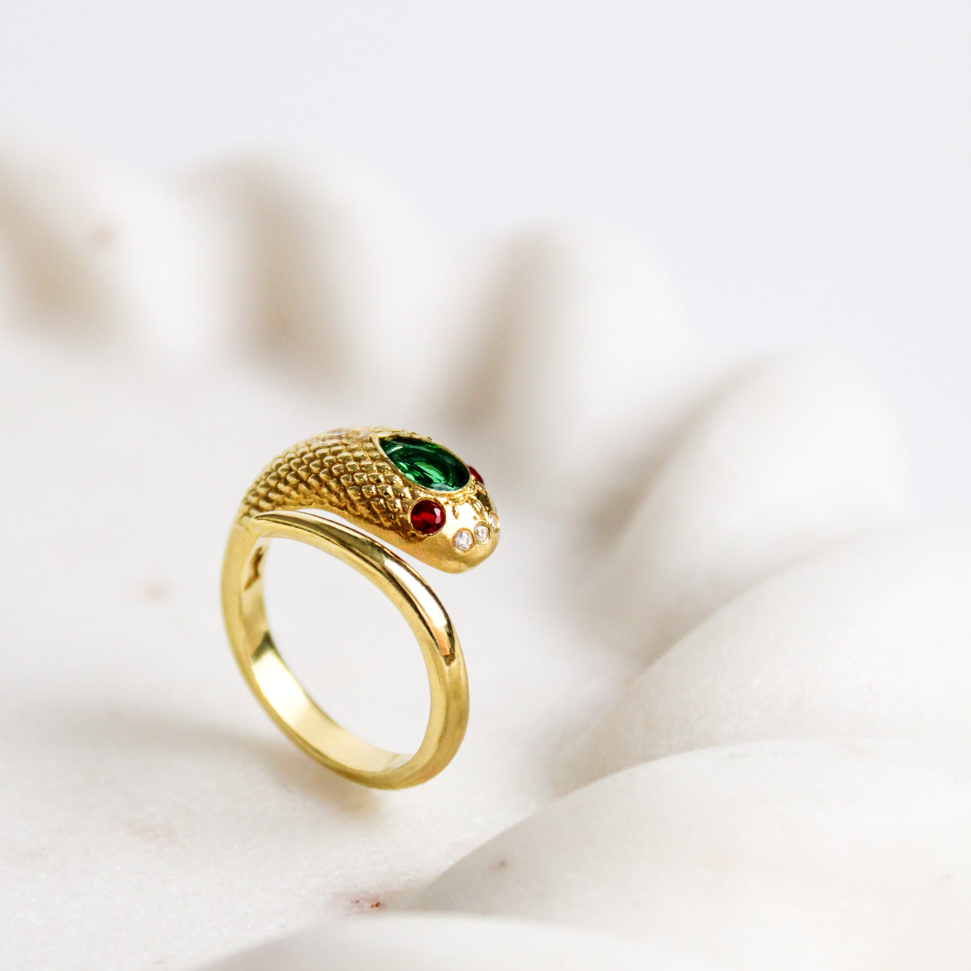 Side profile of Queen Victoria 18k gold vermeil snake ring on marble tray, showcasing detailed scales and gemstones, Ether Jewelry