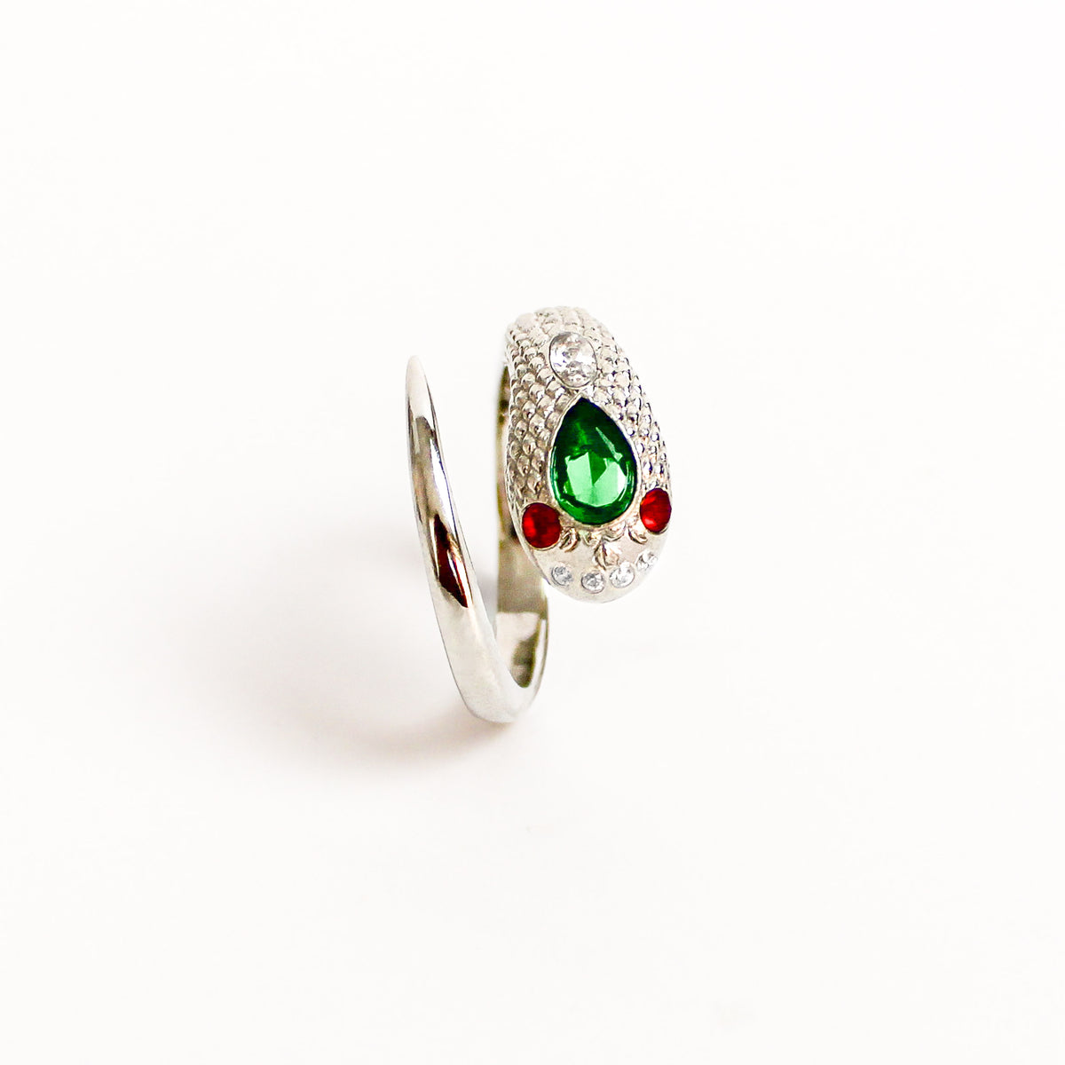 Queen Victoria Ring in sterling silver, snake featuring a prominent green teardrop gemstone on its head, flanked by two small red gemstones and set with clear crystals, shown on a plain white background.