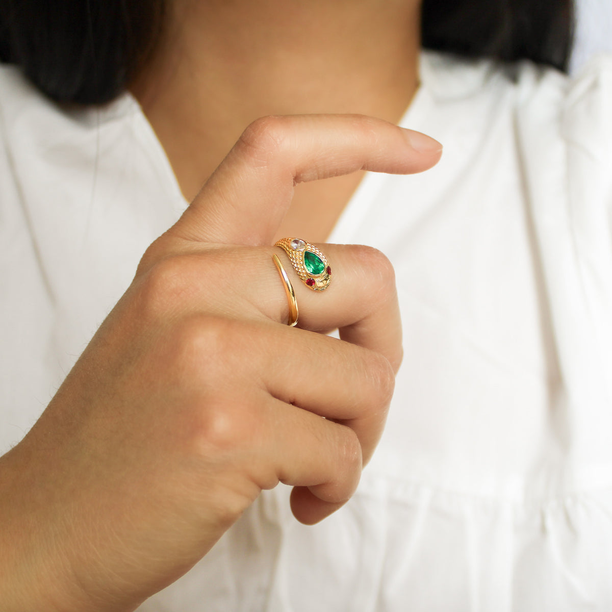 Queen Victoria ring in 14k solid gold on model hand in front of chest, Victorian snake ring with lab-grown emerald and ruby, Ether Jewelry