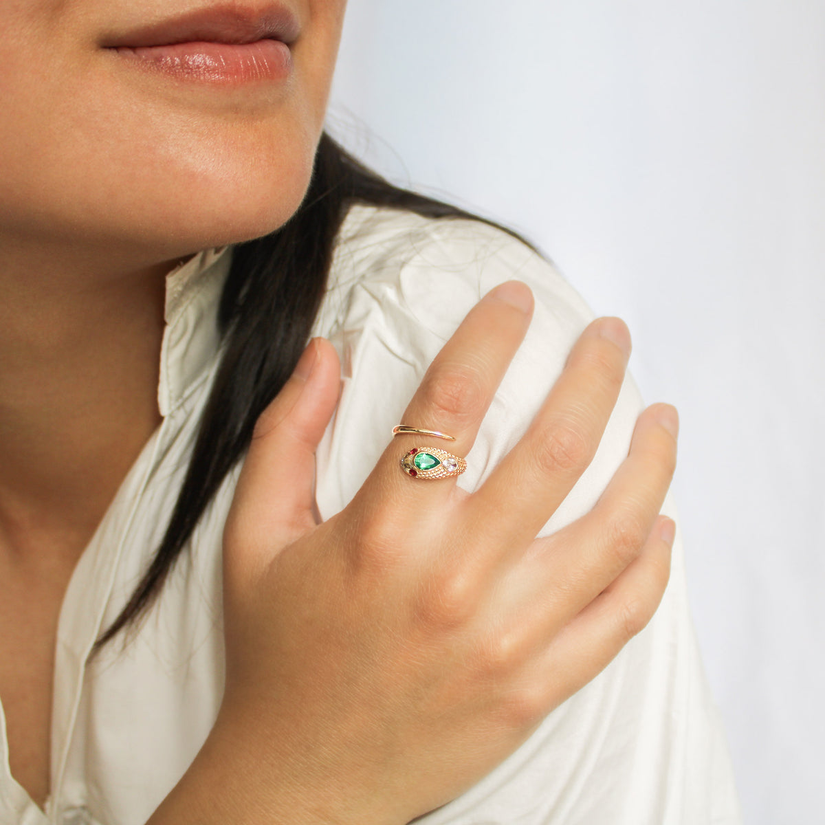 Queen Victoria ring in 14k solid gold on model hand on shoulder smiling, Victorian snake ring with pear emerald and ruby eyes, Ether Jewelry