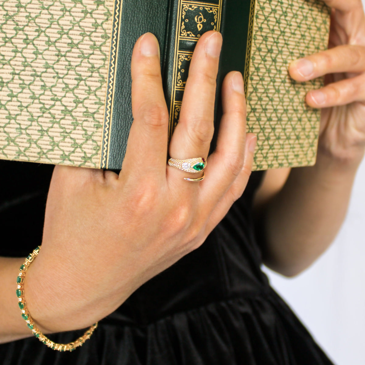 Queen Victoria 14k gold serpent ring on model hand holding up vintage book, lab-grown emerald ruby diamond Victorian ring, detailed scales, Ether Jewelry