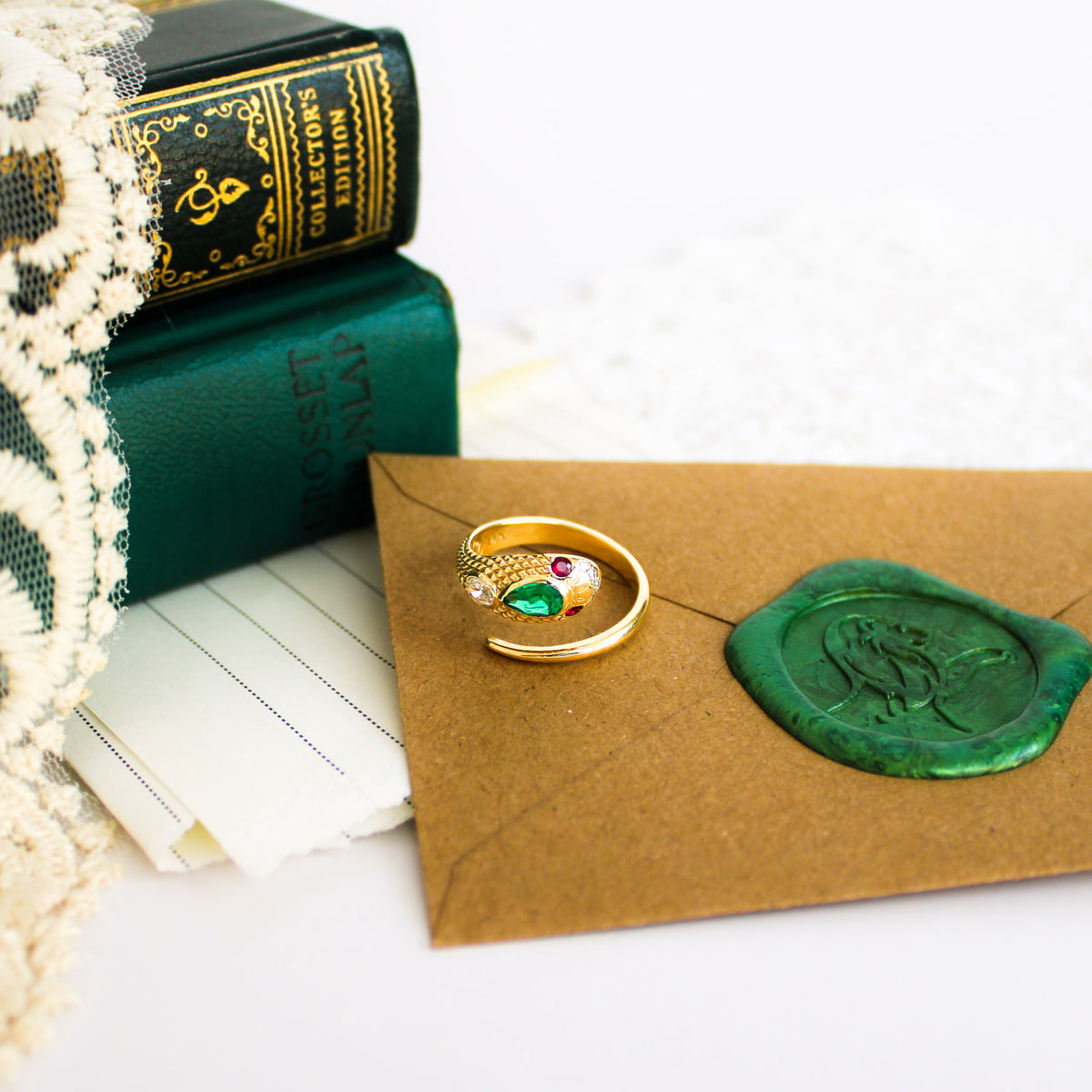 Queen Victoria ring in 14k gold sitting on envelope with vintage books, Victorian inspired serpent ring lab-grown emerald and ruby, Ether Jewelry