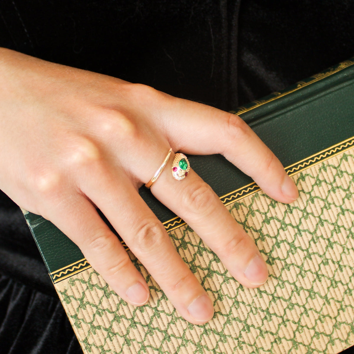 Queen Victoria 14k gold snake ring on hand holding vintage book, Victorian inspired serpent ring with lab-grown emerald and ruby, Ether Jewelry