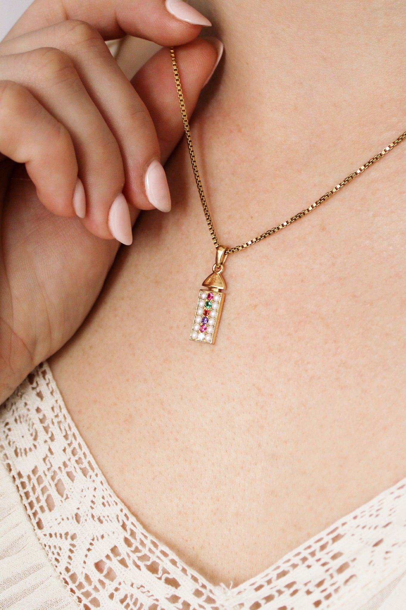Regent Necklace in 18k gold vermeil on model touching pendant, acrostic REGARD pearl-paved rectangular necklace, Ether Jewelry