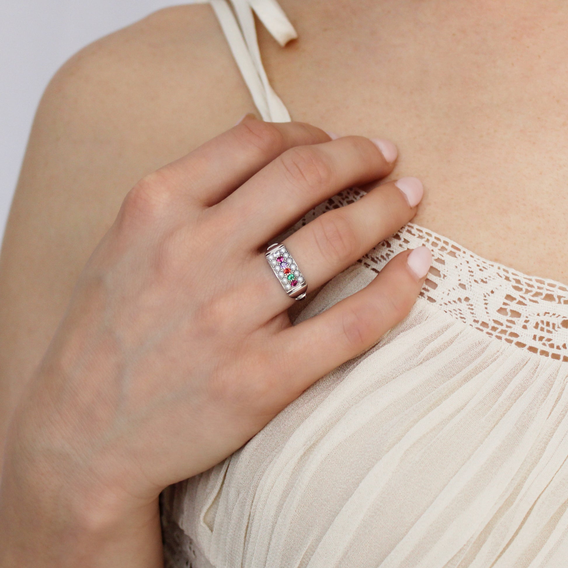 Regent Ring in sterling silver worn on model hand on chest in beige dress, pearl-paved REGARD acrostic signet ring, Ether Jewelry