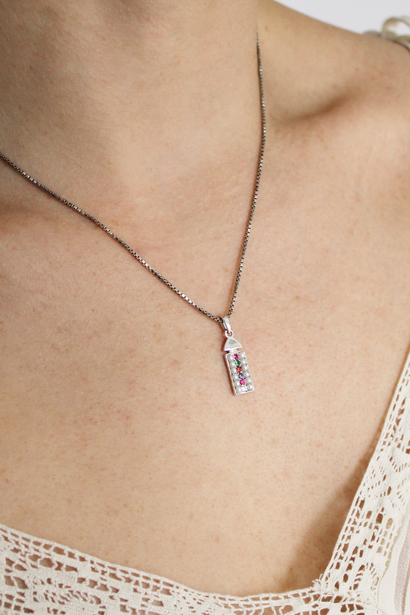 Regent sterling silver necklace on model side view, pearl-paved acrostic rectangular pendant with domed cap, Ether Jewelry
