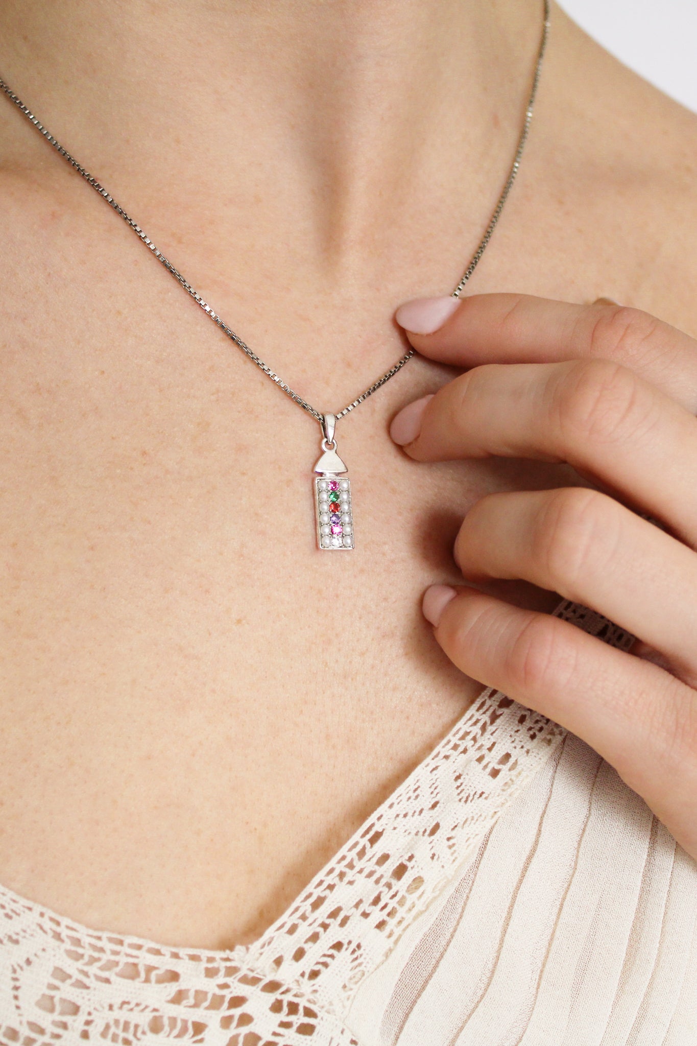 Regent Necklace in sterling silver on model touching pendant, acrostic REGARD pearl-paved rectangular necklace, Ether Jewelry