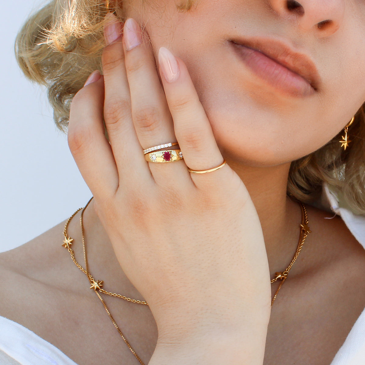 Rose from Roma Ring 18k gold vermeil close-up on model hand, domed pink CZ center with star-set white CZ stones, by model face, Ether Jewelry