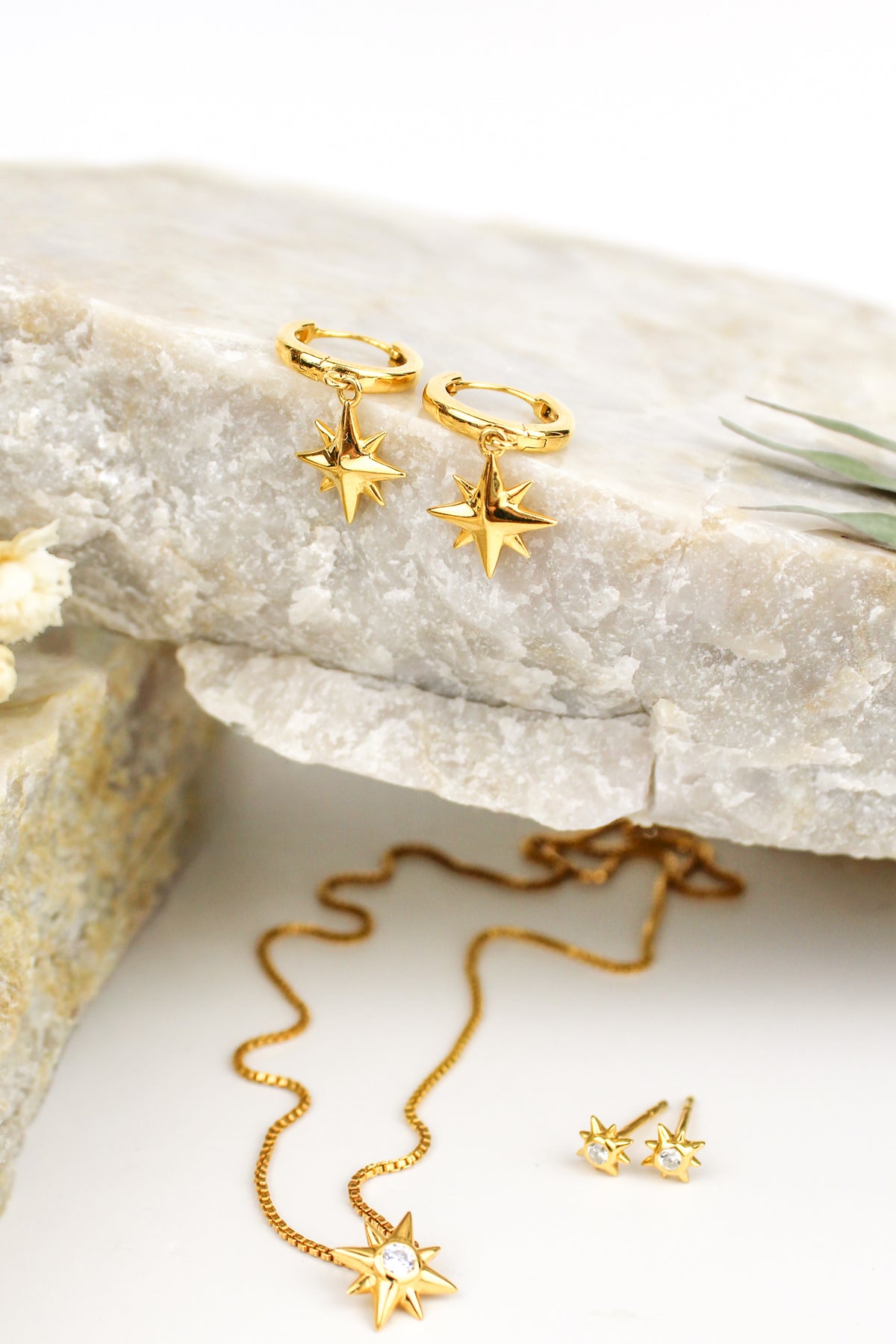 Stella Hoops in 18k gold vermeil staged on marble with other pieces, solid north star huggie hoop earrings, Ether Jewelry