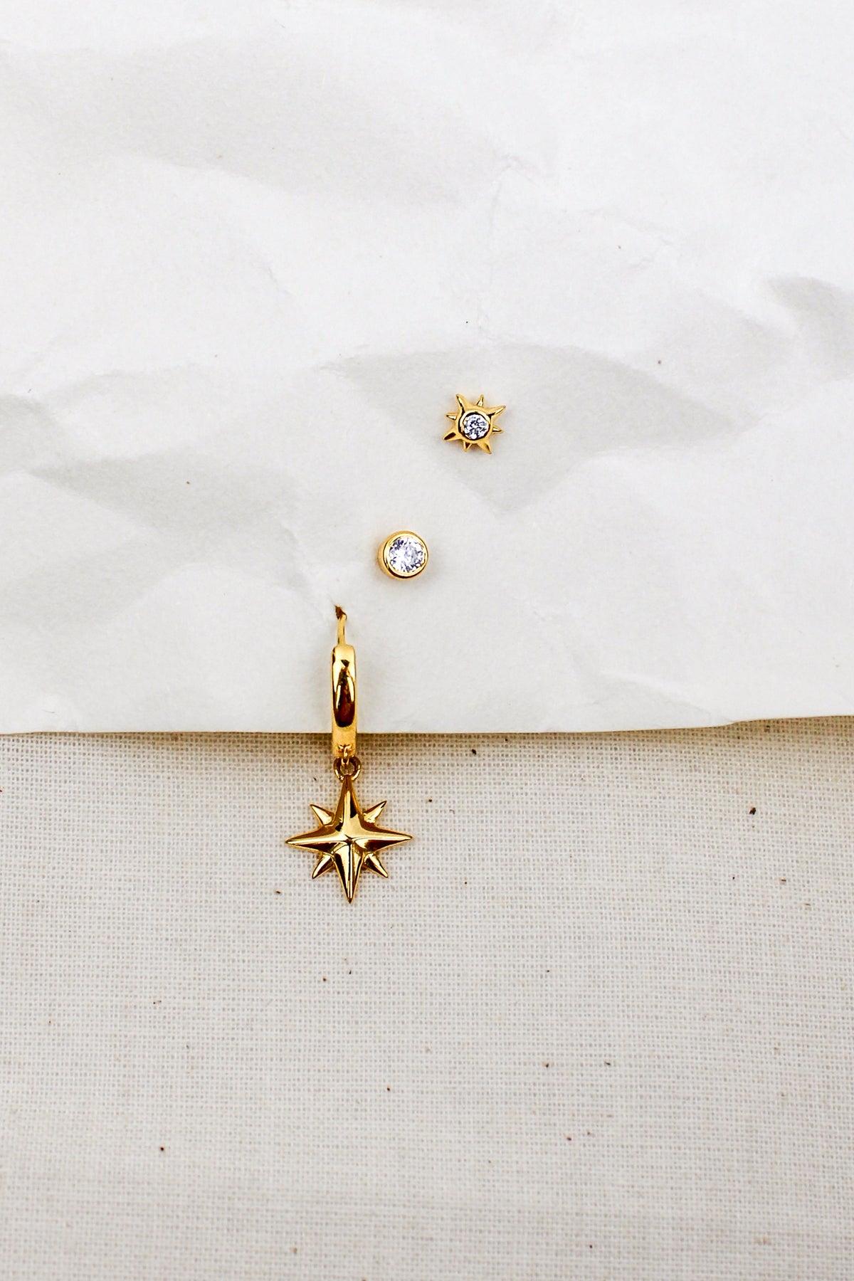 Stella Hoops 18k gold vermeil staged on paper and natural fabric, north star charm drop earrings, Ether Jewelry