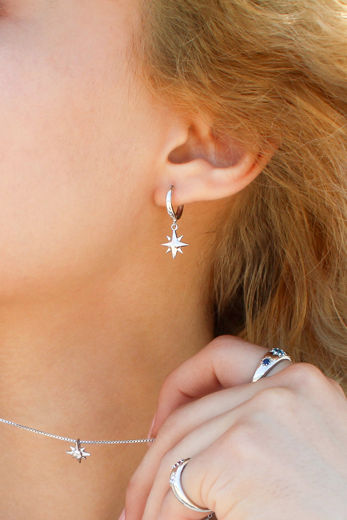 Stella Hoops in sterling silver close-up on model ear, solid north star charm drop huggie hoop earrings, Ether Jewelry