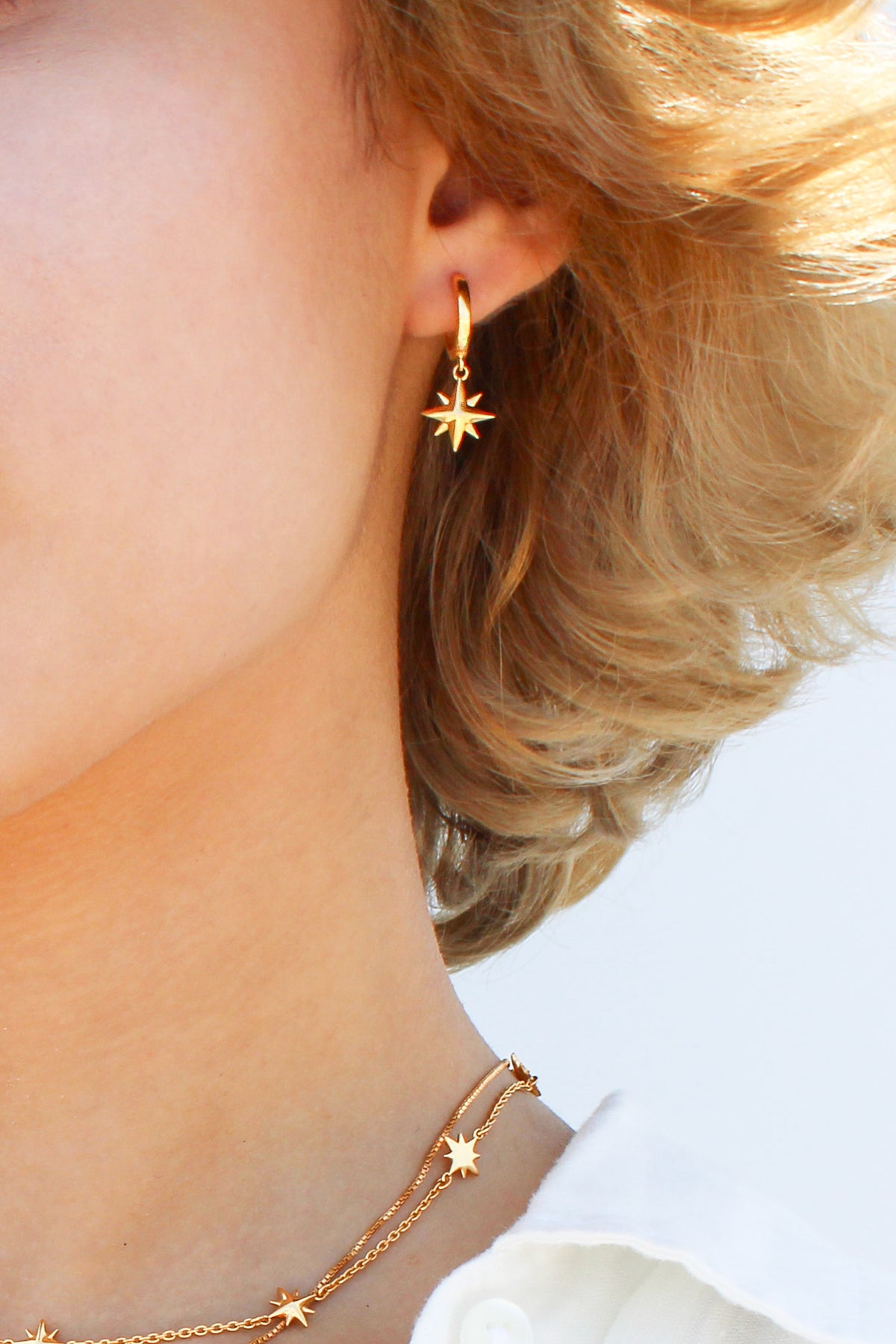 Stella Hoops in 18k gold vermeil close-up on model ear, solid north star charm drop huggie hoop earrings, Ether Jewelry