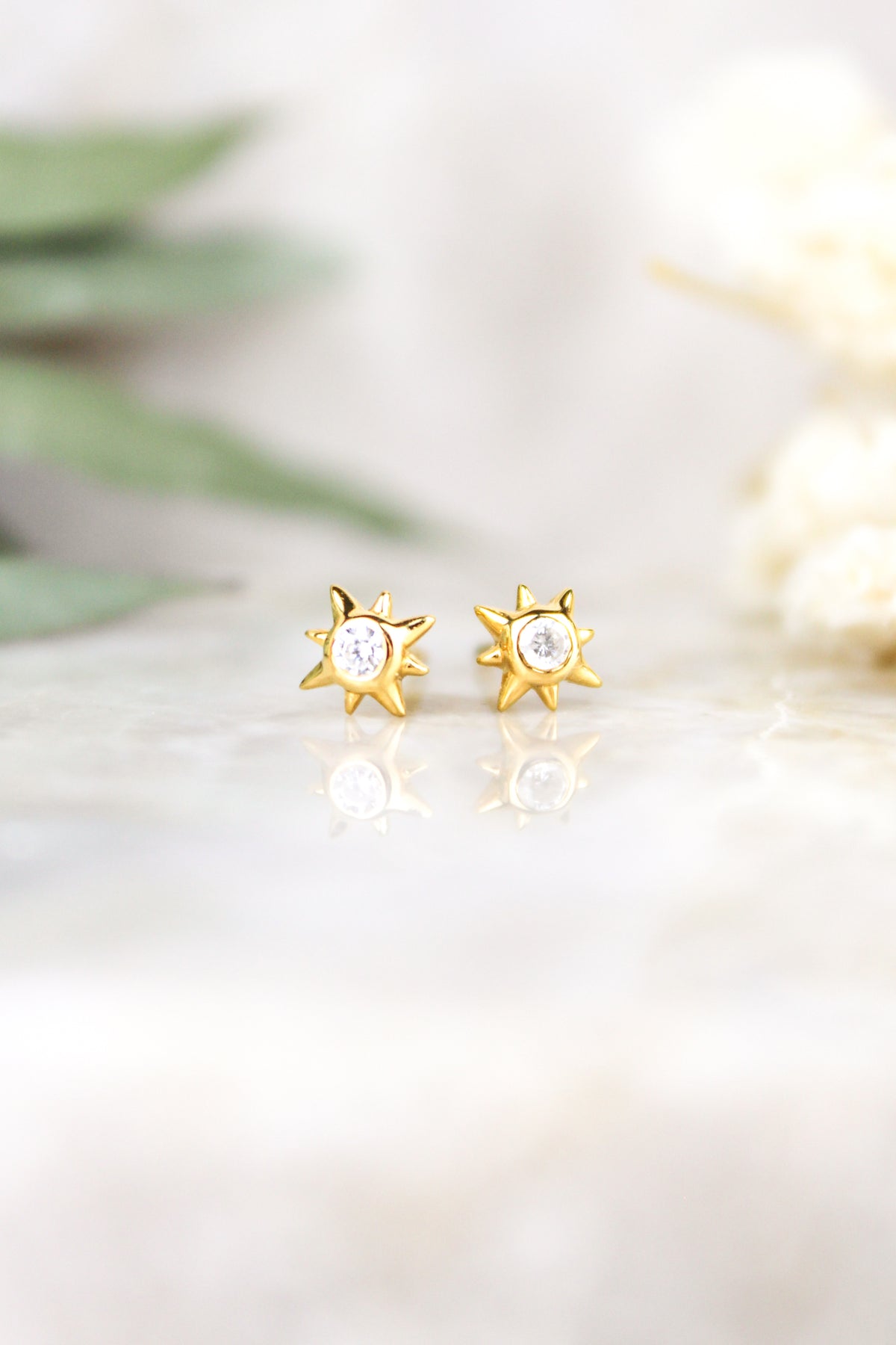 Stella Stud Earrings 18k gold vermeil staged on marble with eucalyptus and white flowers, north star CZ studs, Ether Jewelry
