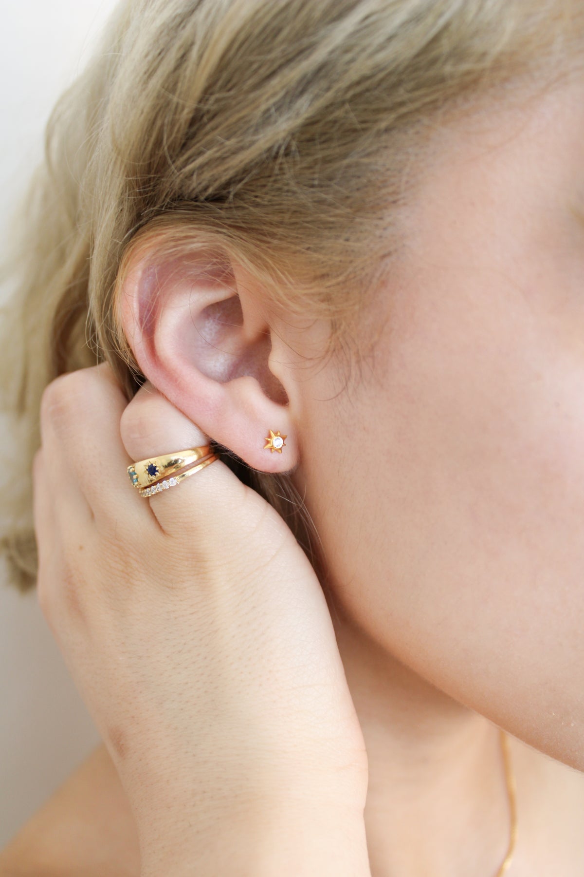 Stella Stud Earrings 18k gold vermeil close-up with model hand next to ear, dainty north star CZ studs, Ether Jewelry