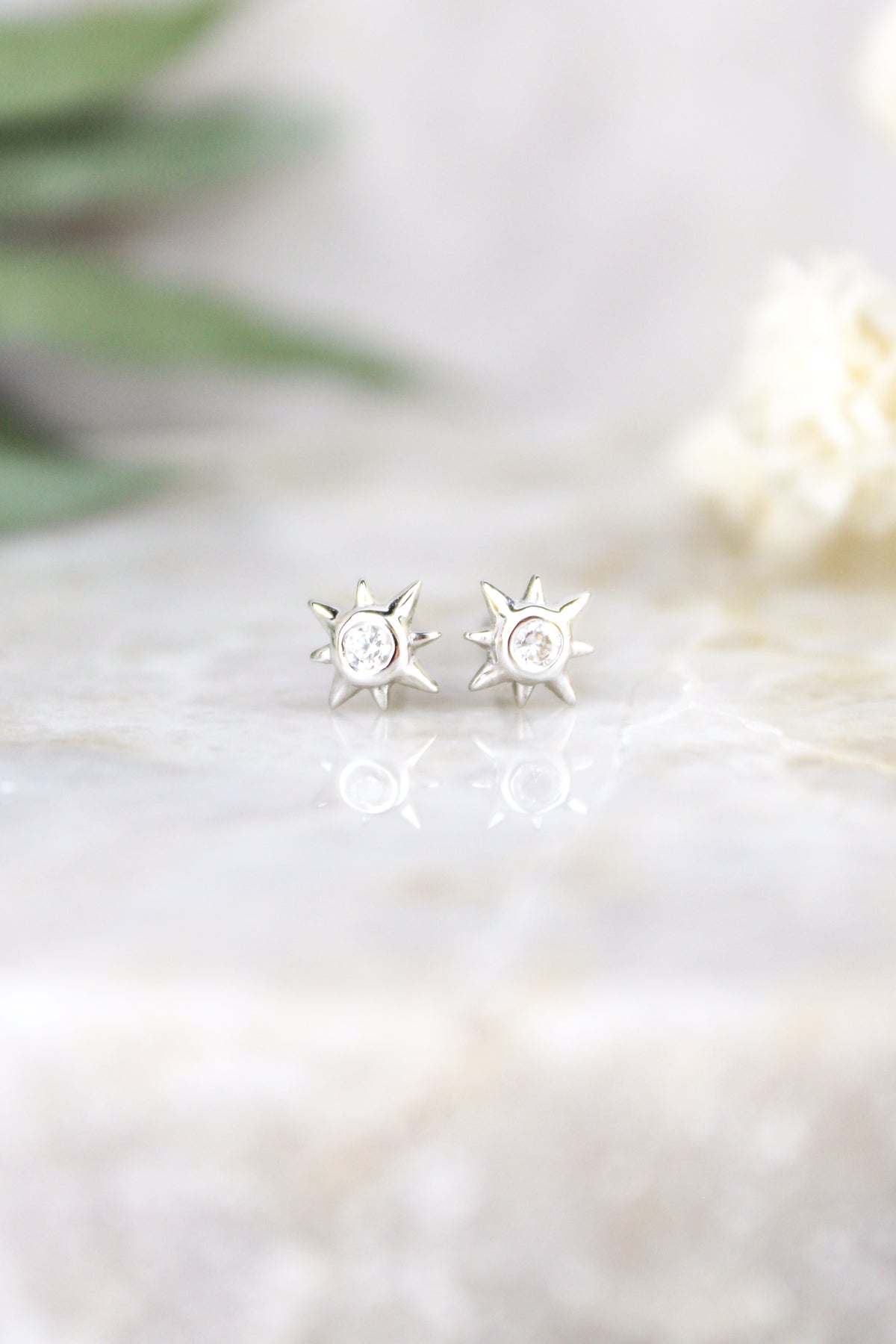Stella Stud Earrings sterling silver staged on marble with eucalyptus and white flowers, north star CZ studs, Ether Jewelry