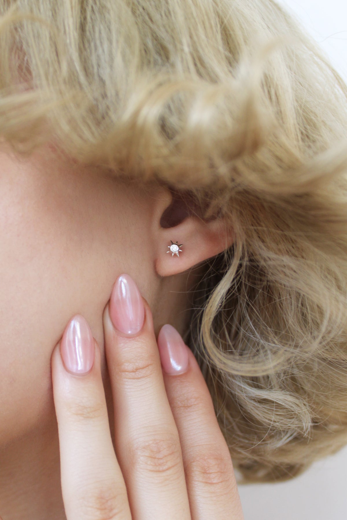 Stella Stud Earrings sterling silver close-up with model hand next to ear, dainty north star CZ studs, Ether Jewelry