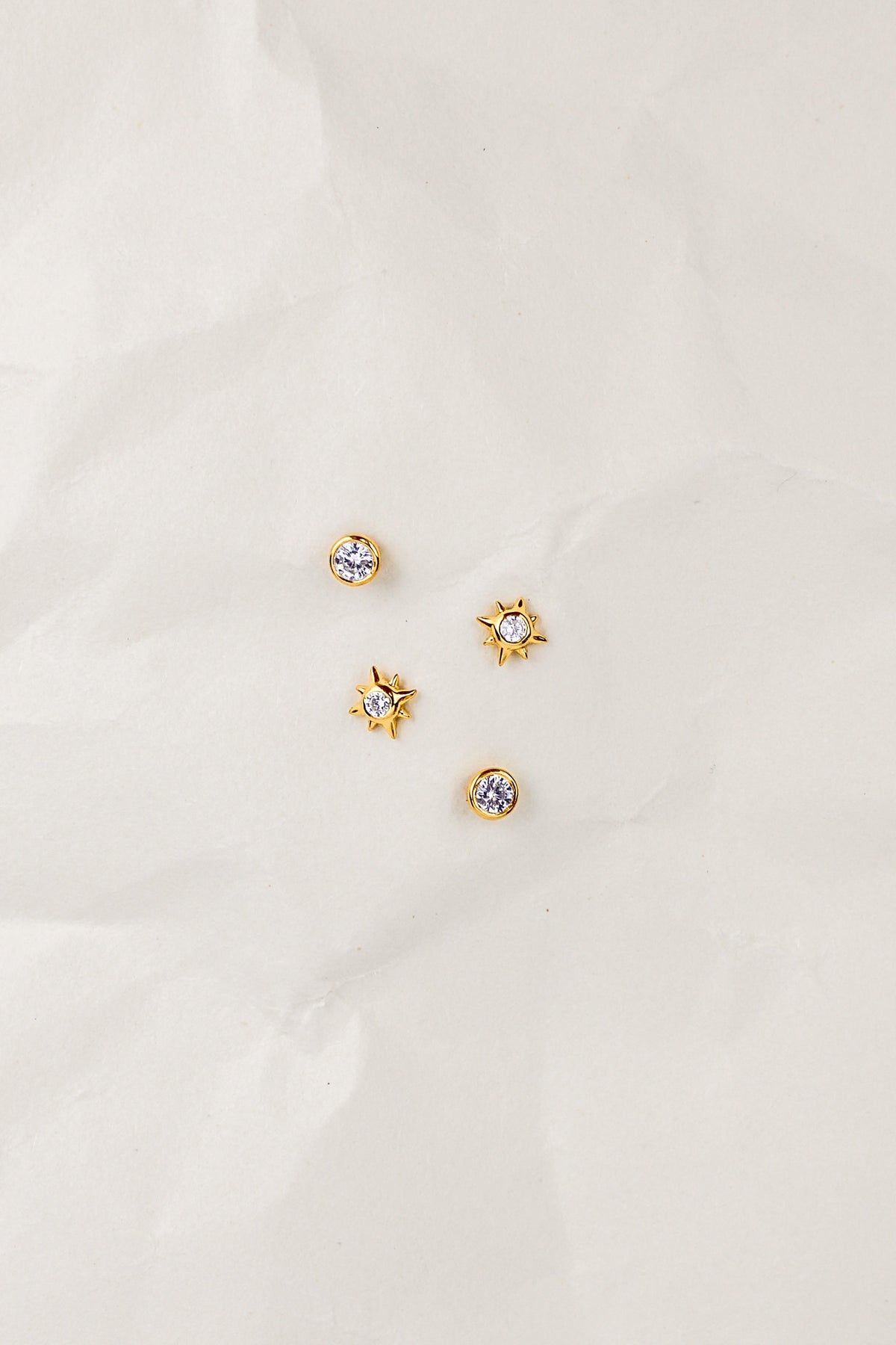 Stella Stud Earrings in 18k gold vermeil staged on crinkled paper, dainty north star CZ stud earrings, Ether Jewelry