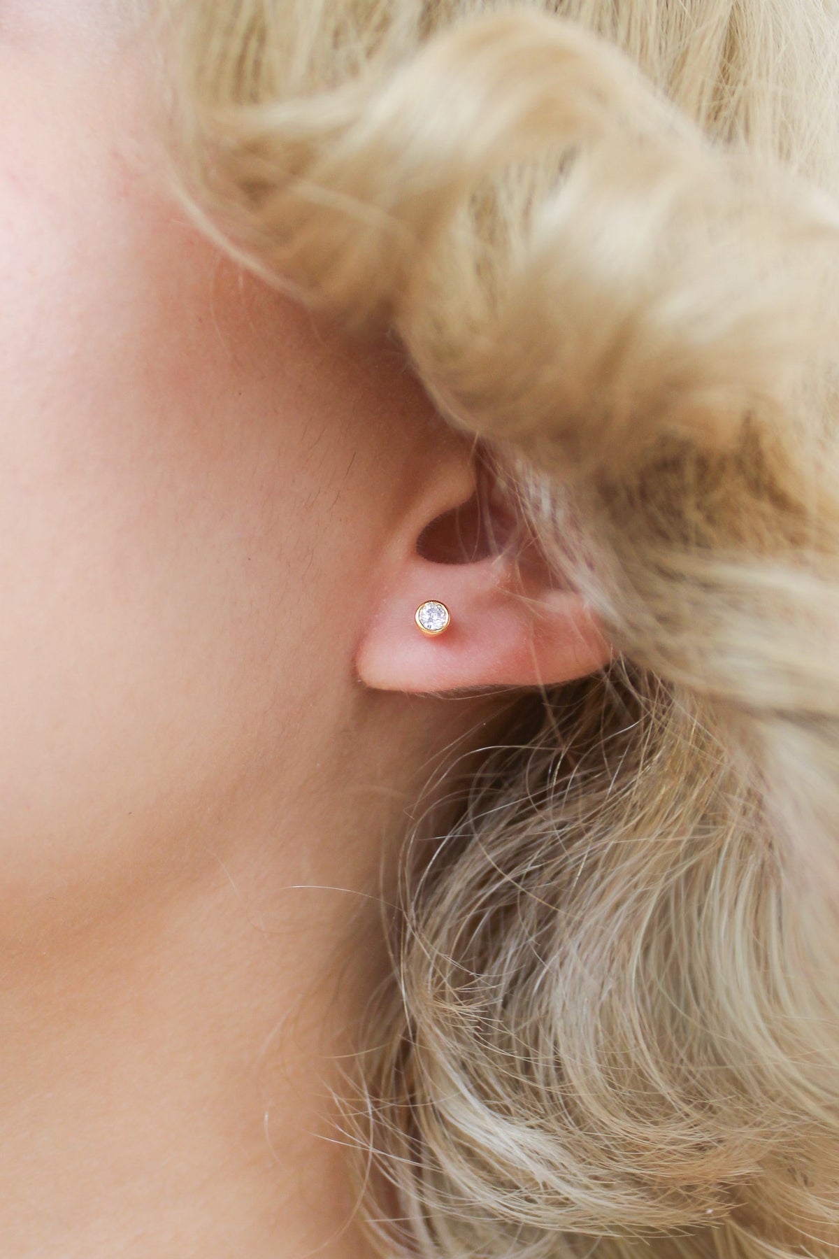 18k gold vermeil Vesta Stud Earrings close-up on model ear, bezel-set round CZ stud earring detail, Ether Jewelry
