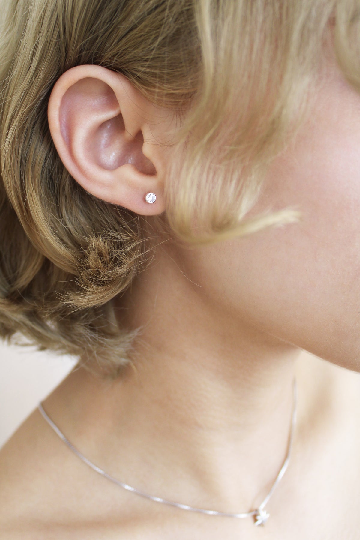 Vesta Stud Earrings in sterling silver on model, dainty bezel-set round CZ stud earrings, Ether Jewelry