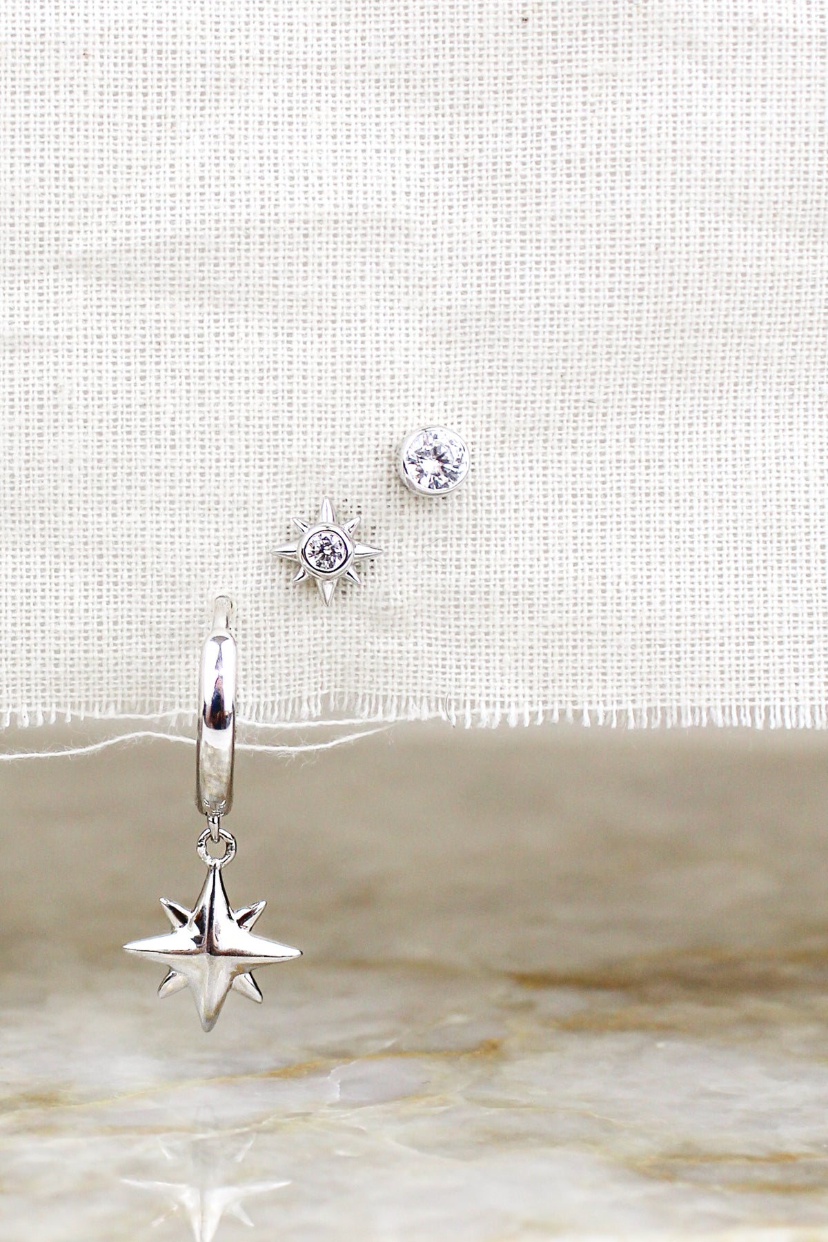 Vesta Stud Earrings sterling silver staged on natural fabric with all three earrings above marble, Ether Jewelry