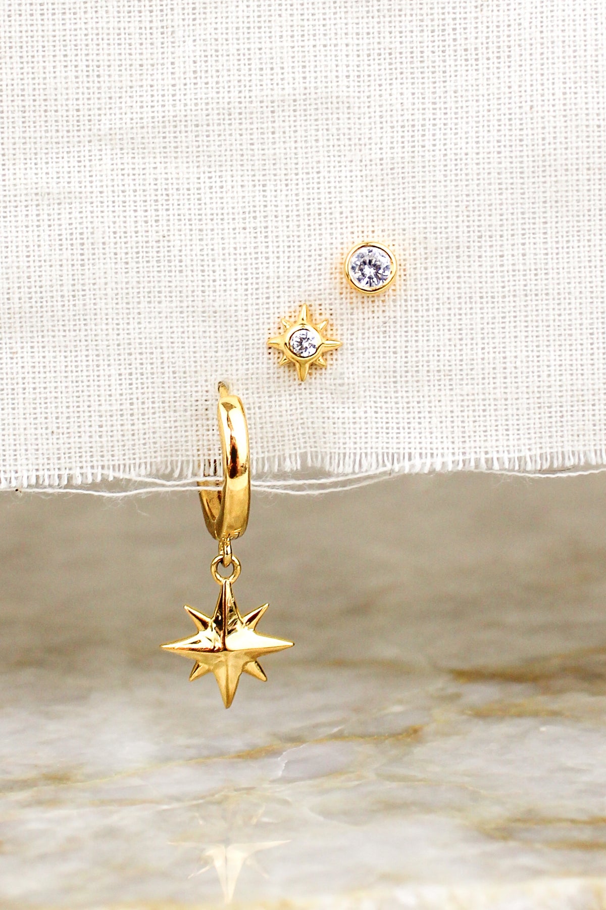 Stella Stud Earrings 18k gold vermeil staged on natural fabric with all three earrings above marble, Ether Jewelry