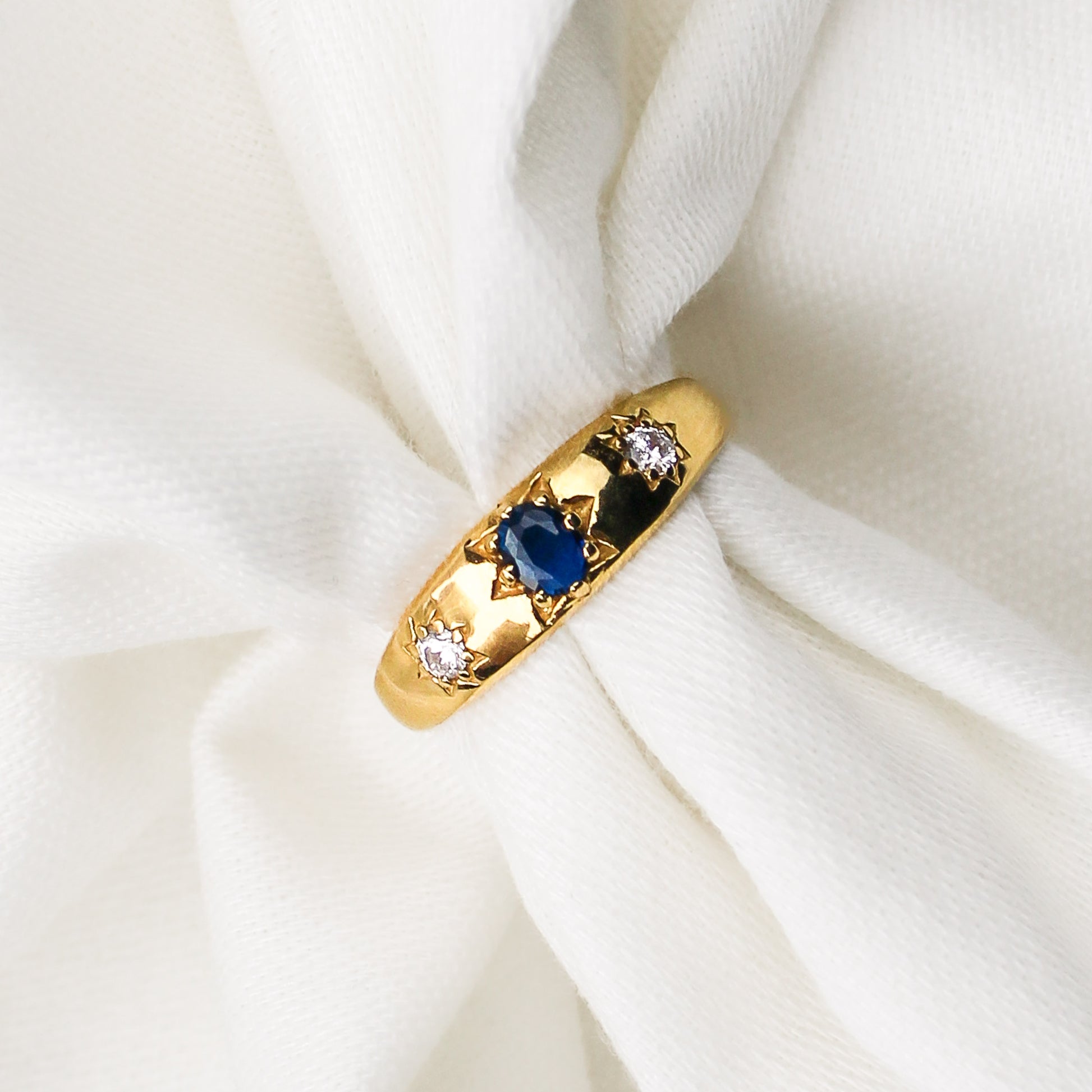 Victorian Roma Ring in 18k gold vermeil, domed gypsy band with blue CZ center and two star-set white CZ side stones on white fabric, Ether Jewelry