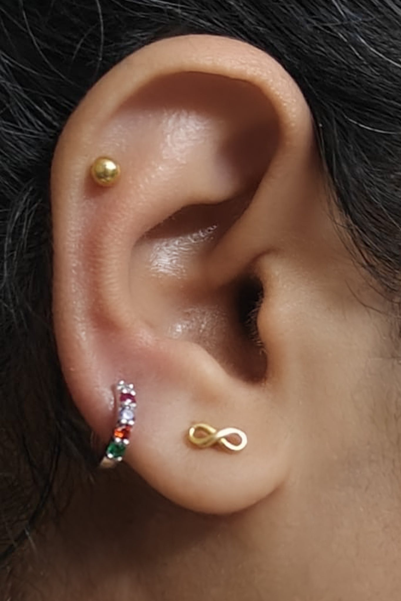 Sterling silver Regard Huggies stacked with other earrings on model ear, acrostic REGARD CZ huggie hoops, Ether Jewelry