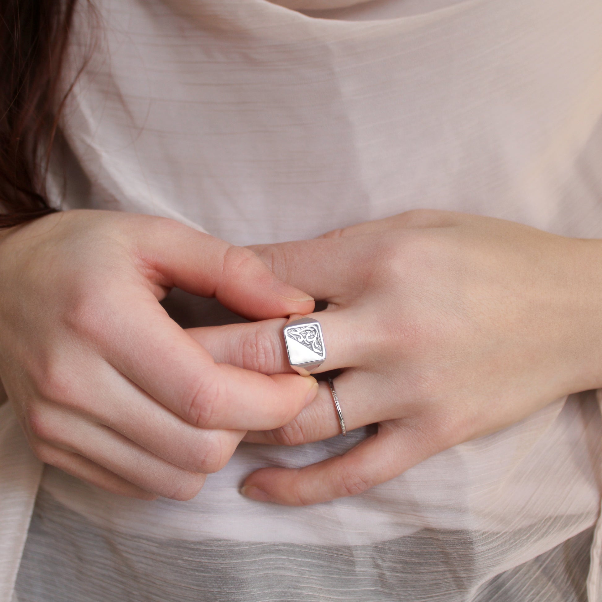 Close-up of hands wearing a sterling silver architect signet ring with a unique design.