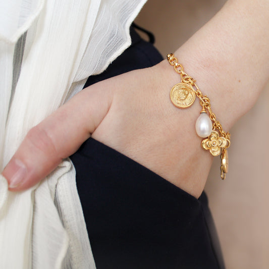 Archivist Bracelet in 18k gold vermeil on model hand in pocket, lion coin pearl flower and north star charm bracelet, Ether Jewelry